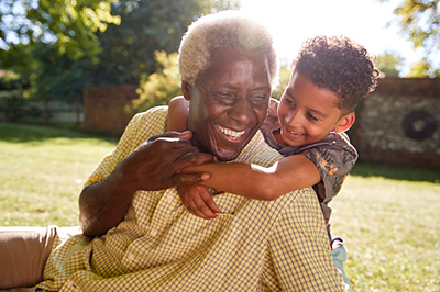 A young boy hugging his grandfather in a park