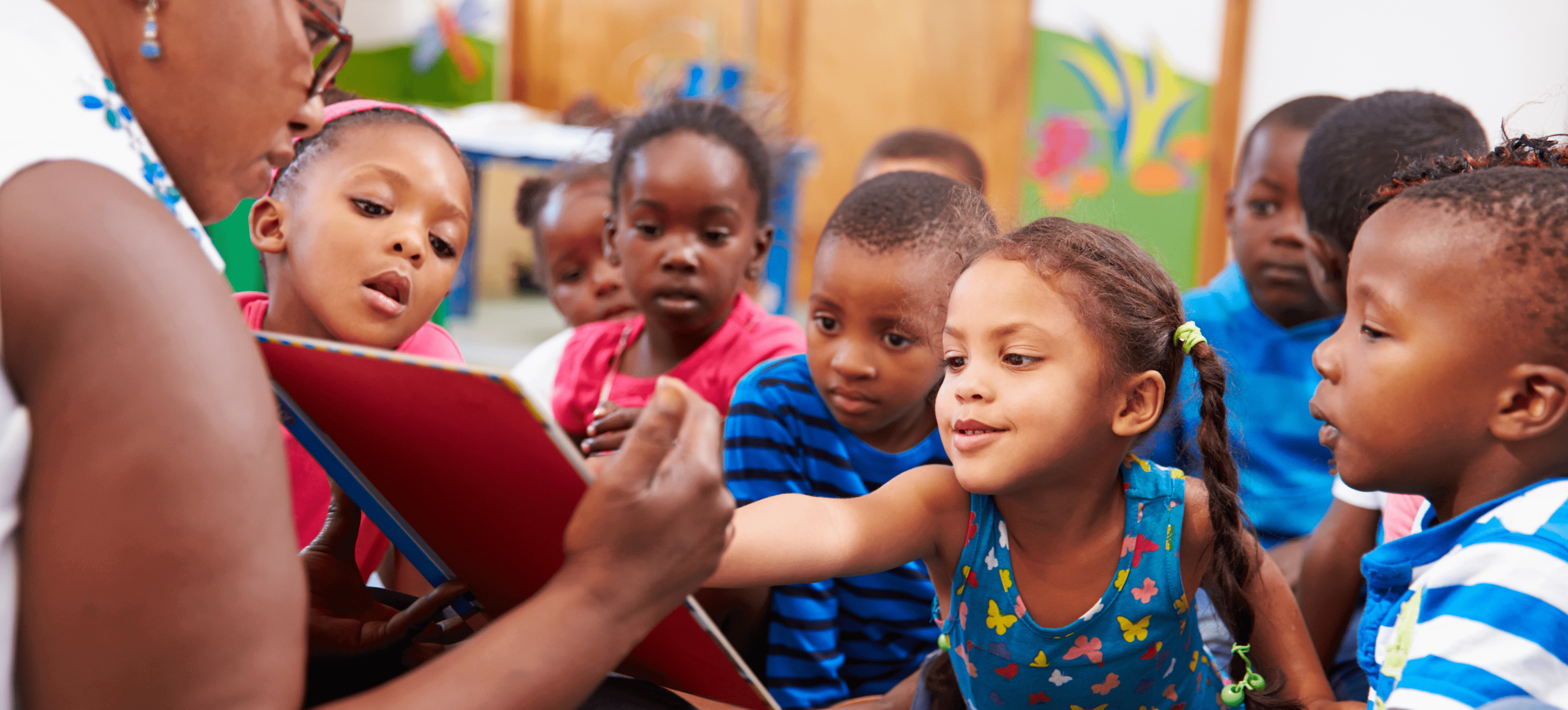 Children gathered around their teacher in a classroom