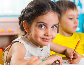 Young smiling girl drawing in a classroom